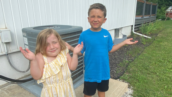 Confused children by an air conditioner